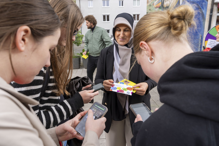 Das Bild zeigt mehrere Mädchen am Infostand, die mit ihren Handys die Umfrage zum neuen Quartiersbüro Innenstadt durchgehen.