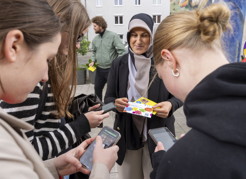 Das Bild zeigt mehrere Mädchen am Infostand, die mit ihren Handys die Umfrage zum neuen Quartiersbüro Innenstadt durchgehen. 
