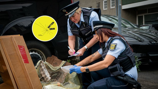 Das Bild zeigt eine Streife der Waste Watcher mt zwei Frauen, die illegal abgelegten Müll nach Hinweisen auf den Verursacher durchsuchen. 