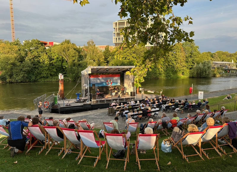 Das Bild zeigt eine Musikveranstaltung von Kultur am Fluss mit vielen Gästen vor der schwimmenden Fährlebühne im Neckar.