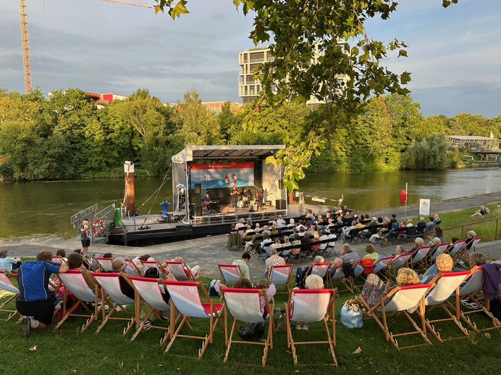 Das Bild zeigt eine Musikveranstaltung von Kultur am Fluss mit vielen Gästen vor der schwimmenden Fährlebühne im Neckar.