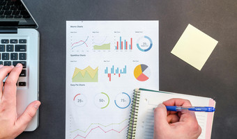 Das Themenbild zur Mikrozensus-Umfrage zeigt eine Tischplatte mit Block, Stift, Taschenrechner und einem Blatt Papier mit verschiedenen Grafiken. 