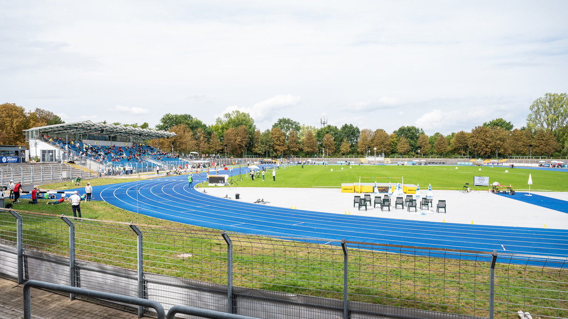 Das Bild zeigt das Frankenstadion in Heilbronn mit der blauen Laufbahn, dem Fußballrasen und der Tribüne. 