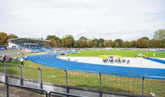 Das Bild zeigt das Frankenstadion in Heilbronn mit der blauen Laufbahn, dem Fußballrasen und der Tribüne. 