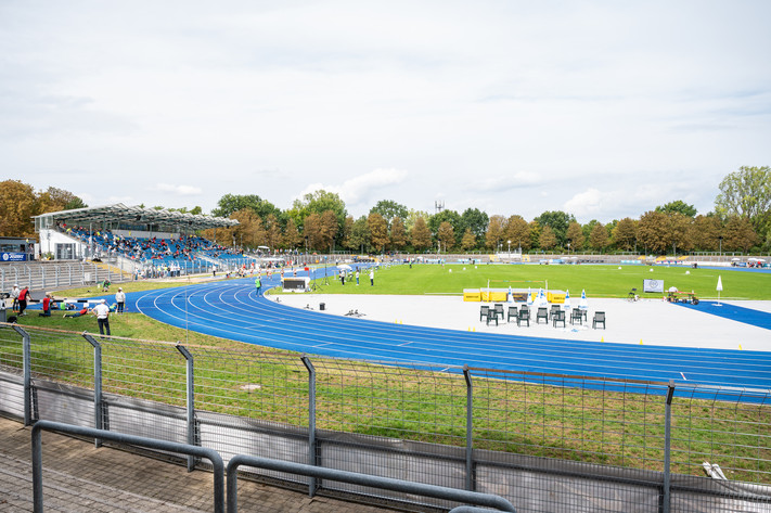 Das Bild zeigt das Frankenstadion in Heilbronn mit der blauen Laufbahn, dem Fußballrasen und der Tribüne. 