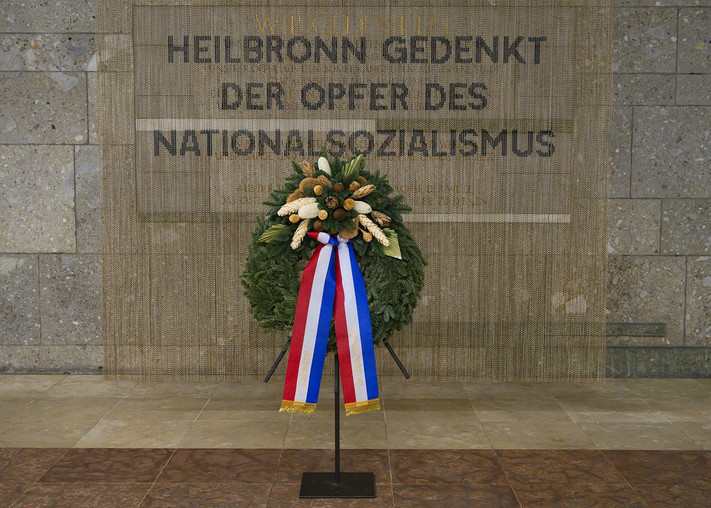 Das Bild zeigt einen Ehrenkranz mit Schleifen in Heilbronn-Farben vor einer Inschrift "Der Opfer des Nationalsozialismus". 