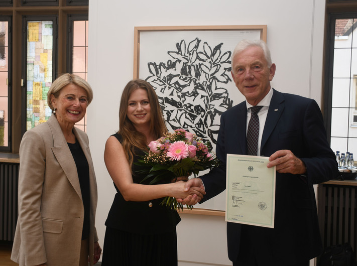 Das Bild zeigt Oberbürgermeister Harry Mergel, wie er Sigida Hajdari gratuliert und die Einbürgerungsurkunde bereithält. Bürgermeisterin Agnes Christner freut sich mit über die neue Bestmarke. 