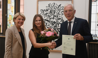 Das Bild zeigt Oberbürgermeister Harry Mergel, wie er Sigida Hajdari gratuliert und die Einbürgerungsurkunde bereithält. Bürgermeisterin Agnes Christner freut sich mit über die neue Bestmarke. 