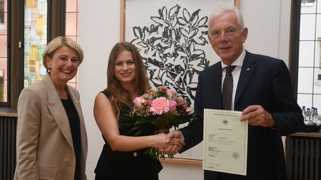 Das Bild zeigt Oberbürgermeister Harry Mergel, wie er Sigida Hajdari gratuliert und die Einbürgerungsurkunde bereithält. Bürgermeisterin Agnes Christner freut sich mit über die neue Bestmarke.