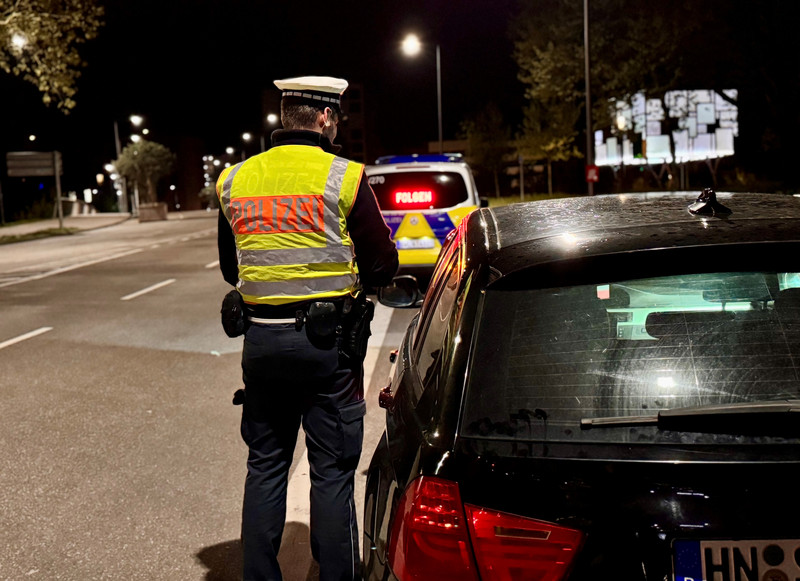 Ein Polizeibeamter kontrolliert einen Autofahrer in einer Straße im nächtlichen Heilbronn.