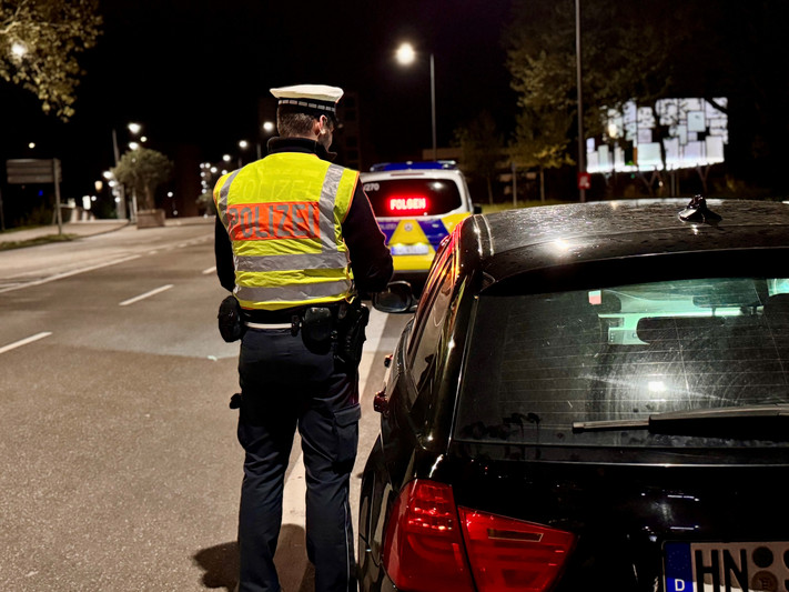 Ein Polizeibeamter kontrolliert einen Autofahrer in einer Straße im nächtlichen Heilbronn.