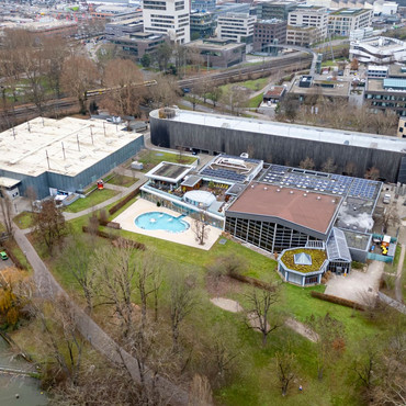 Luftaufnahme des Freizeitbads Soleo, der Eishalle und des Parkhauses am Bollwerksturm, umgeben von Grünflächen und weiteren Stadtgebäuden.
