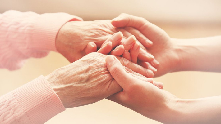 Das Bild zeigt vier Hände, die sich umfassen als Symbolbild für die Hilfe von Berufsbetreuerinnen und Betreuerinnen für Menschen mit Beeinträchtigungen. 