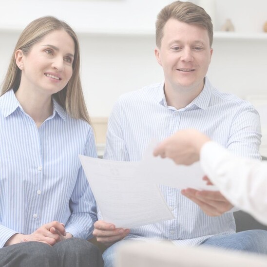 Man sieht ein Paar, das ein Dokument überreicht bekommt