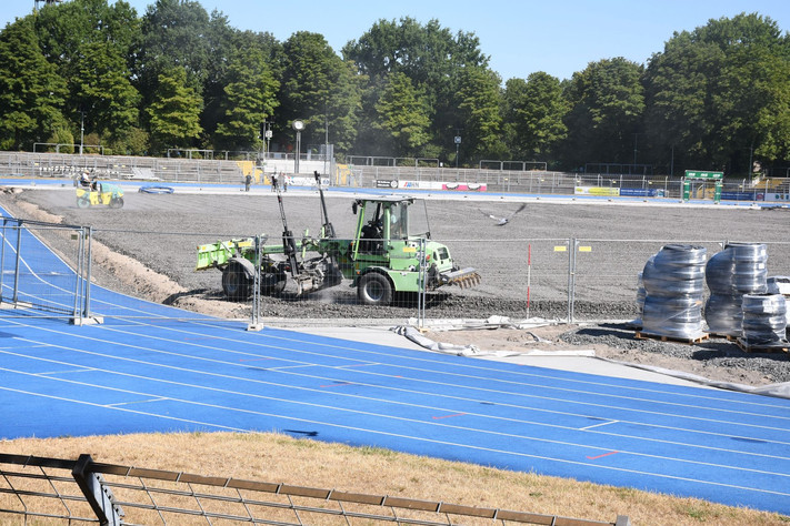 Das Bild zeigt Baumaschinen im Einsatz auf dem geschotterten Untergrund des Spielfeldes im Frankenstadion. Vorarbeiten für den Einbau einer Rasenheizung sind im Gange.