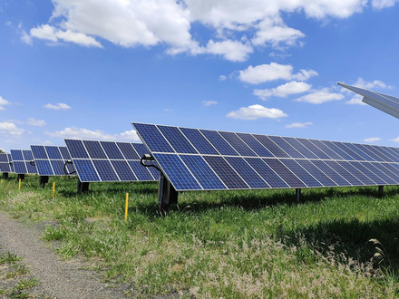 Auf dem Foto ist eine Freiflächen Photovoltaikanlage unter blauem Himmel mit Schäfchenwolken zu sehen