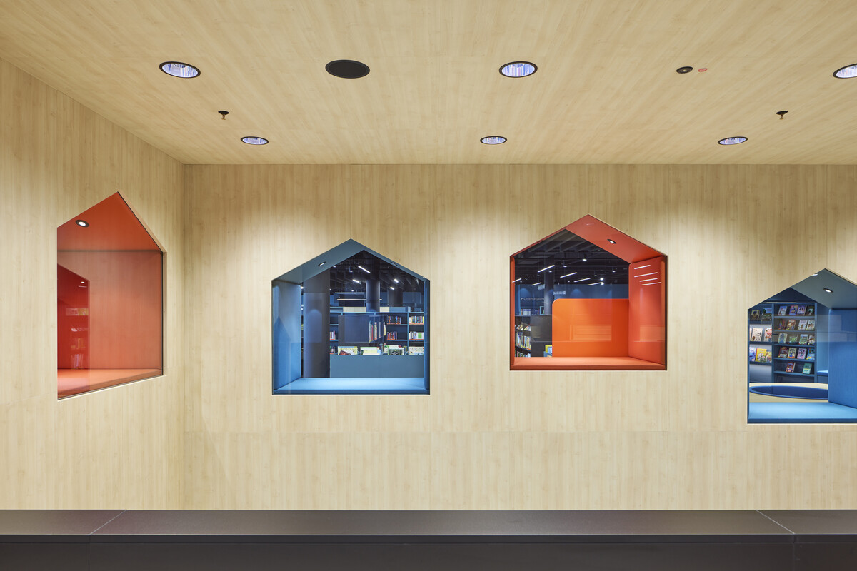 Man sieht den Innenraum des Treppenhauses der Bibliothekt: Fenster in Form von kleinen Häusern in Orange und Blau