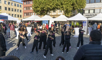 Das Bild zeigt eine Gruppe Schülerinnen und Schüler bei einer Tanzvorführung auf dem Marktplatz. 