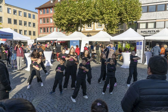 Das Bild zeigt eine Gruppe Schülerinnen und Schüler bei einer Tanzvorführung auf dem Marktplatz. 