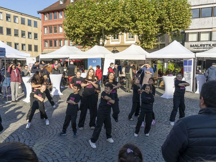 Das Bild zeigt eine Gruppe Schülerinnen und Schüler bei einer Tanzvorführung auf dem Marktplatz. 