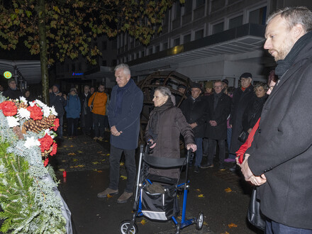 Das Bild zeigt Menschen beim Gedenken an die Reichspogromnacht im Vorjahr am Gedenkstein an der Allee.