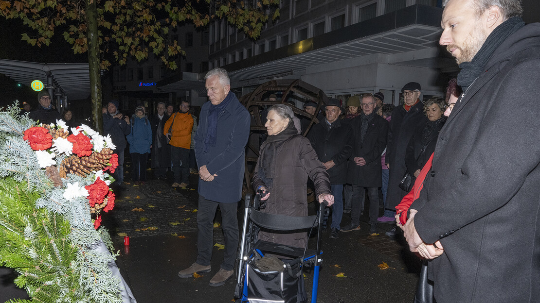 Das Bild zeigt Menschen beim Gedenken an die Reichspogromnacht im Vorjahr am Gedenkstein an der Allee.