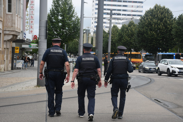 Man sieht drei Mitarbeiter des Kommunalen Ordnungsdienstes der Stadt Heilbronn auf Streife an der Allee.