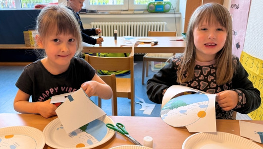 Sophie (links) und Paula schneiden die Vorlage aus, um sie anschließend auf den Pappteller zu kleben. Dann wird in der Mitte noch ein Wassertropfen befestigt, der sich entlang des Wasserkreislaufs dreht.