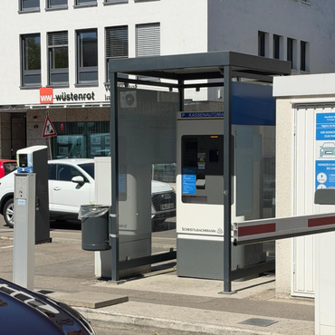 Parkautomat an einer Schrankenanlage in Heilbronn vor einem Gebäude mit Wüstenrot Filiale im Hintergrund