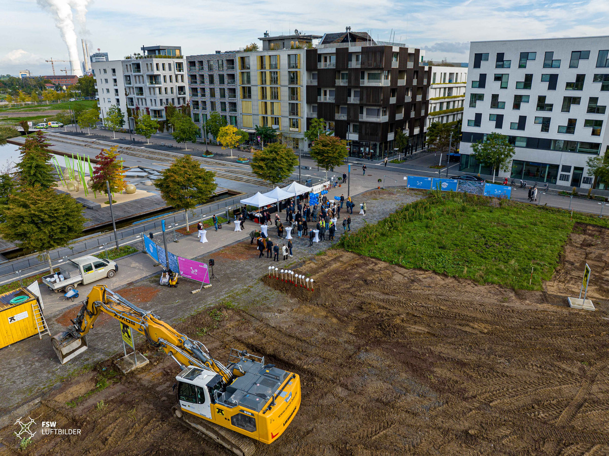 Ein Luftbild. Man sieht einen gelben Bagger auf dem zweiten Bauabschnitt sowie die Schaufeln für den Spatenstich.