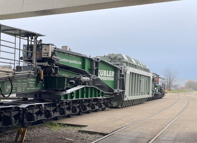 Das Bild zeigt den Transport eines schweren Transformators auf den Hafenbahngleisen.