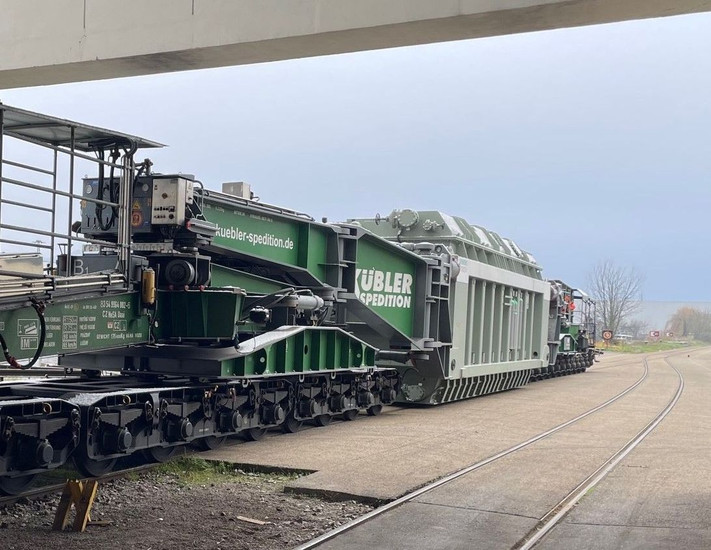 Das Bild zeigt den Transport eines schweren Transformators auf den Hafenbahngleisen.