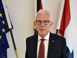 Oberbürgermeister Harry Mergel Der Oberbürgermeister steht vor einem Fahnenmast. Er hat einen Anzug an und eine Krawatte. Er trägt eine Brille.
