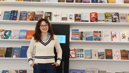 Junge Frau steht vor Bücherregal