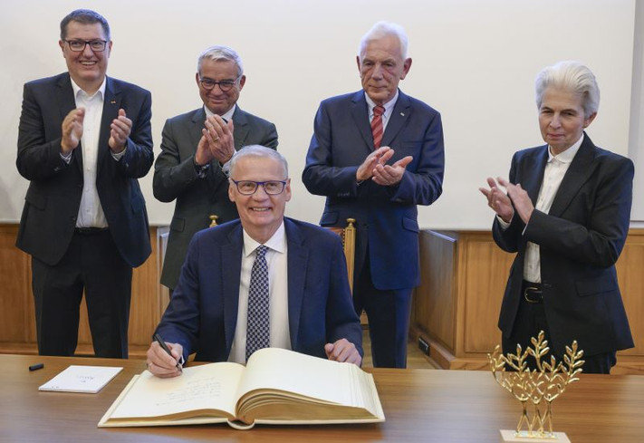 Das Bild zeigt TV-Moderator Günter Jauch, wie er sich bei einem Besuch ins Goldene Buch der Stadt Heilbronn einträgt.