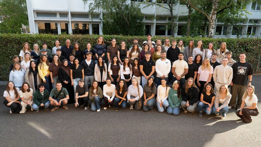 Eine große Gruppe neuer Auszubildender und Studierender der Stadt Heilbronn steht gemeinsam im Freien vor einem Gebäude.
