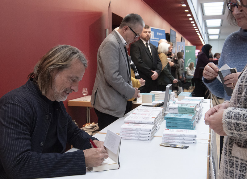 Das Bild zeigt Autor Richard David Precht beim Signieren seiner Bücher.