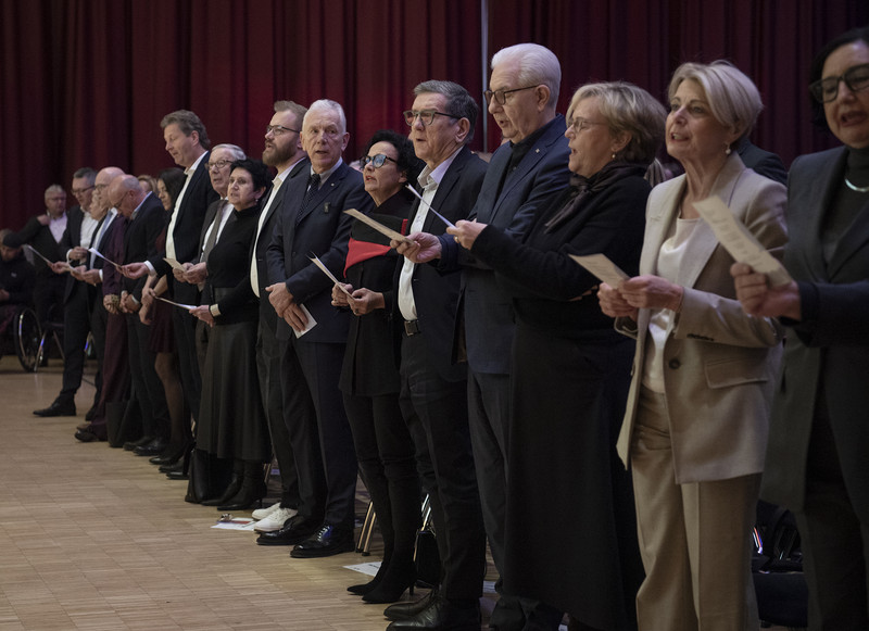 Das Bild zeigt die vordere Stuhlreihe mit vielen Prominenten, die beim Abschlusslied "Kein schöner Land" wie der ganze Saal eifrig mitsangen.