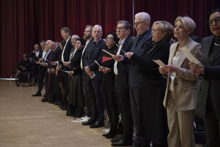 Das Bild zeigt die vordere Stuhlreihe mit vielen Prominenten, die beim Abschlusslied "Kein schöner Land" wie der ganze Saal eifrig mitsangen. 