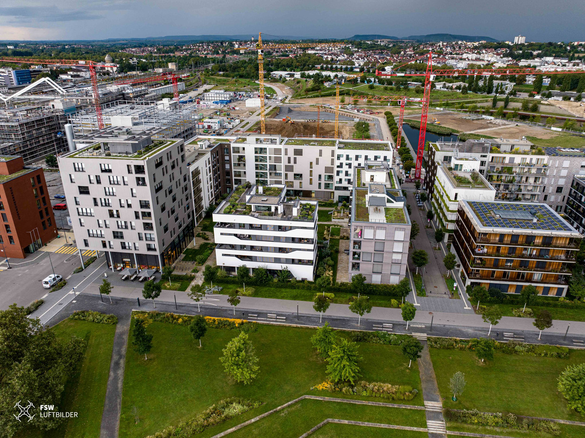 Hinter dem 1. Bauabschnitt ragen die Krane in die Höhe. Bereits heute wohnen im Neckarbogen ca. 600 Menschen.