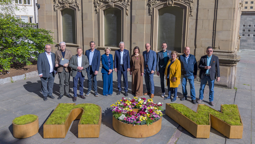 Viele Menschen stehen hinter einem großen Blumengefäß, dass die Buchstaben now darstellt. Die Menschen heiißen: (von links) Baubürgermeister Andreas Ringle, Erster Bürgermeister Martin Diepgen, Stadtrat Nico Weinmann (FDP), Stadtrat Thomas Randecker (CDU), Sozialbürgermeisterin Agnes Christner, Oberbürgermeister Harry Mergel, Projektleiterin Dr. Julia Hufnagel, Geschäftsführer HMG Steffen Schoch, Stadtrat Holger Kimmerle, Stadträtin Marianne Kugler-Wendt, Stadtrat Herbert Burkhardt, Stadtrat Dr. Raphael Benner. Foto: Stadt Heilbronn/Jürgen Häffner