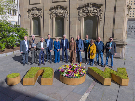 Viele Menschen stehen hinter einem großen Blumengefäß, dass die Buchstaben now darstellt. Die Menschen heiißen: (von links) Baubürgermeister Andreas Ringle, Erster Bürgermeister Martin Diepgen, Stadtrat Nico Weinmann (FDP), Stadtrat Thomas Randecker (CDU), Sozialbürgermeisterin Agnes Christner, Oberbürgermeister Harry Mergel, Projektleiterin Dr. Julia Hufnagel, Geschäftsführer HMG Steffen Schoch, Stadtrat Holger Kimmerle, Stadträtin Marianne Kugler-Wendt, Stadtrat Herbert Burkhardt, Stadtrat Dr. Raphael Benner. Foto: Stadt Heilbronn/Jürgen Häffner