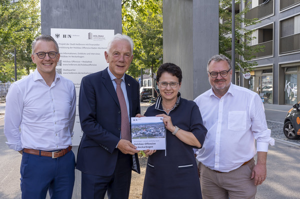 Übergabe der Projektergebnisse vor der Holzstele am Holz-Hochhaus SKAIO. v.l.n.r.: Dominik Buchta, OB Harry Mergel, Ministerin Marion Gentges, BM Andreas Ringle; Foto: Stadt Heilbronn/Jürgen Häffner