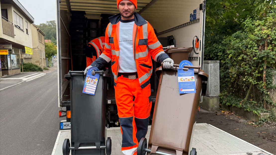 Das Bild zeigt einen Mitarbeiter einer Entsorgungsfirma, der die neuen Restmüll-  und Biotonnen mit integriertem Chip ausliefert. 