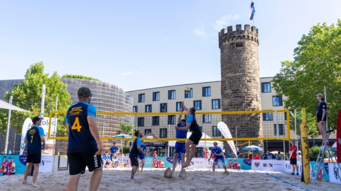 Ein Team spielt Beachvolleyball auf einem Feld vor dem Bollwerksturm