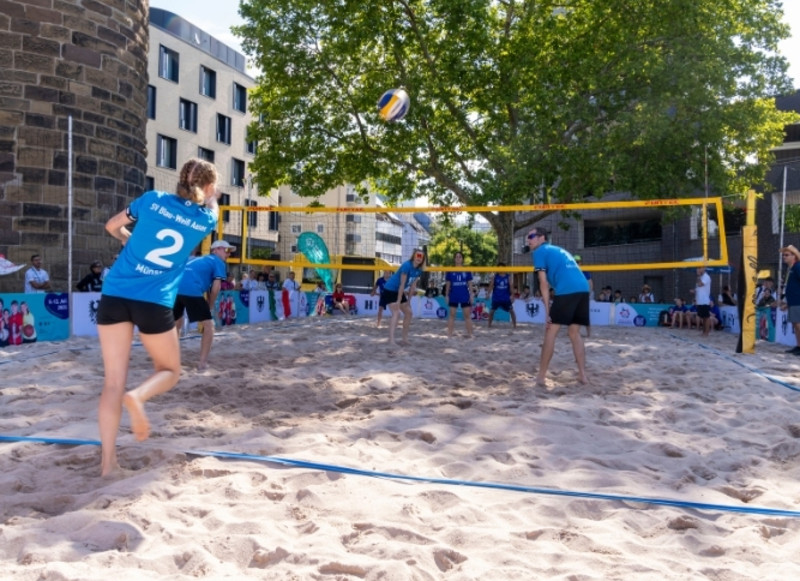 Ein Team spielt Beachvolleyball auf einem Feld vor dem Bollwerksturm