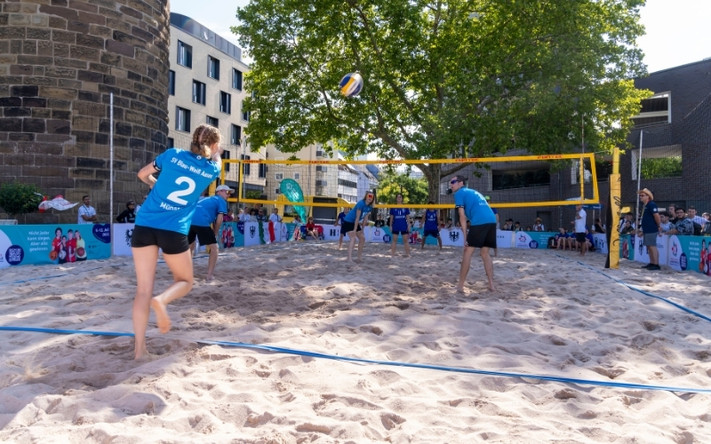 Ein Team spielt Beachvolleyball auf einem Feld vor dem Bollwerksturm