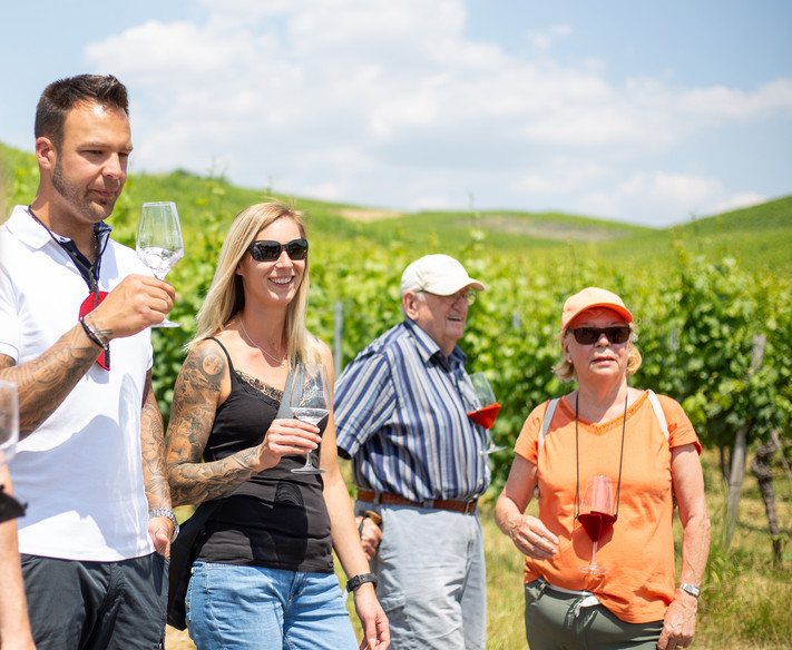 Eine Gruppe Menschen mit Weingläsern innerhalb der Weinberge