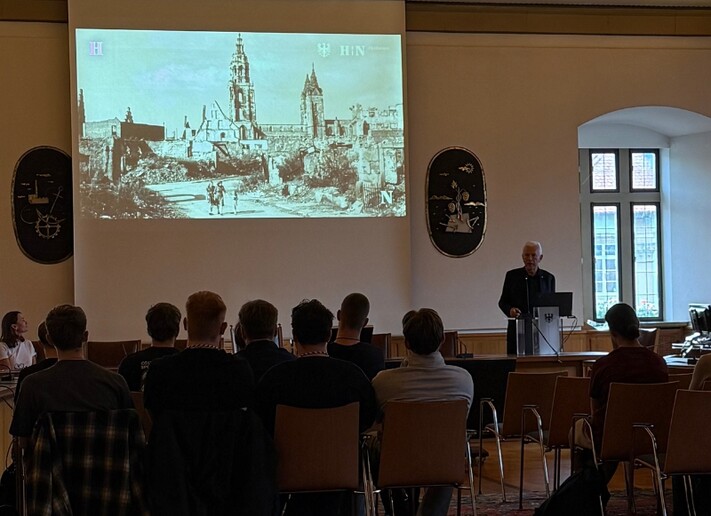 Auszubildende und Studierende sitzen im Großen Ratssaal und verfolgen eine Präsentation zur Stadt Heilbronn.