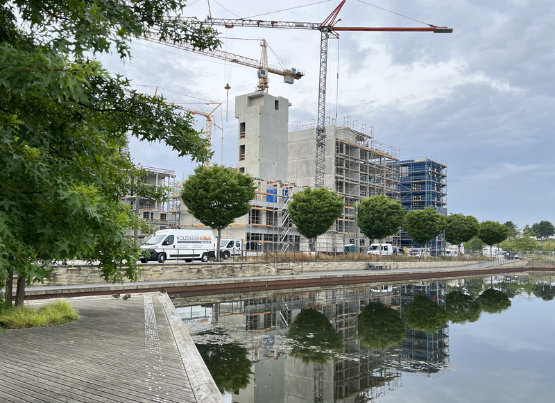 Im Neckarbogen sind große Baukräne vor hohen Gebäuden im Rohbau zu sehen.